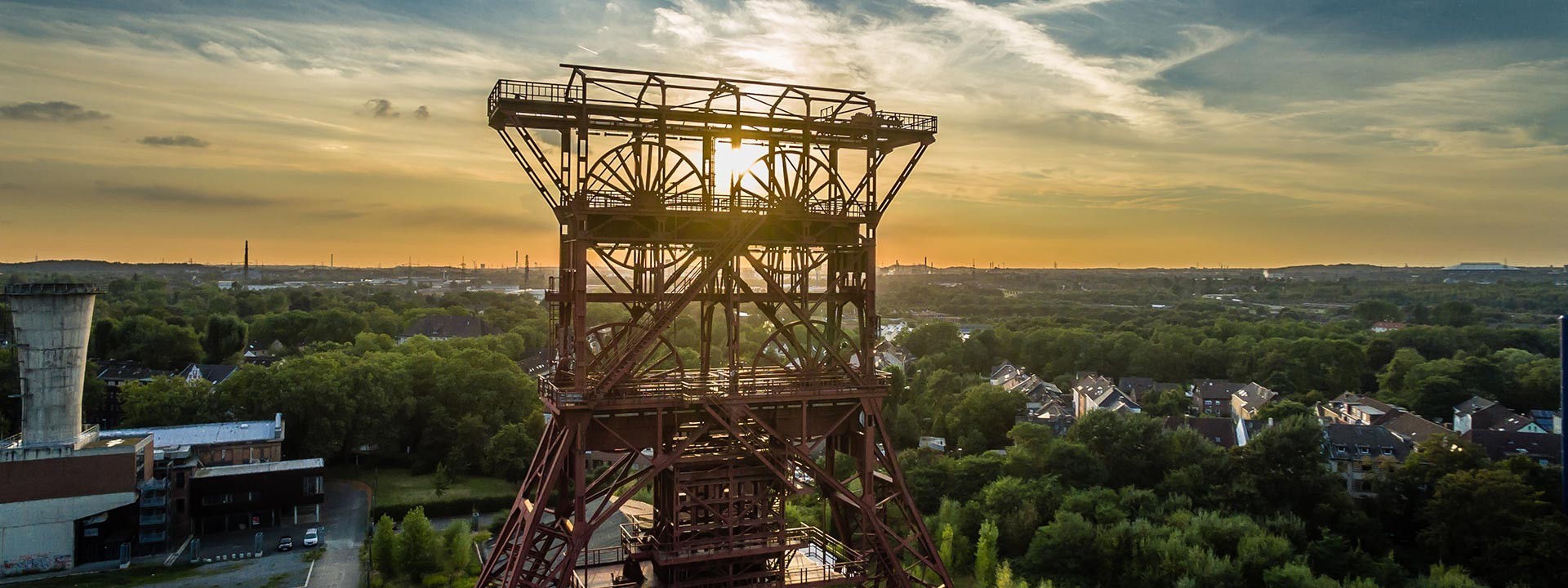 The winding tower of a mine in Dortmund. In the background, the city with the sun on the horizon.